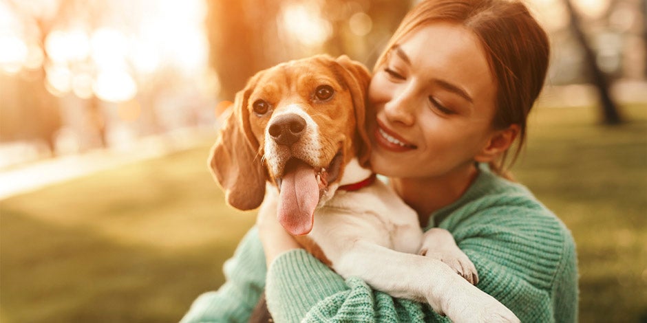 Tutora abrazando un beagle. Aprende a cuidar a tu mascota en casos de epilepsia en perros.