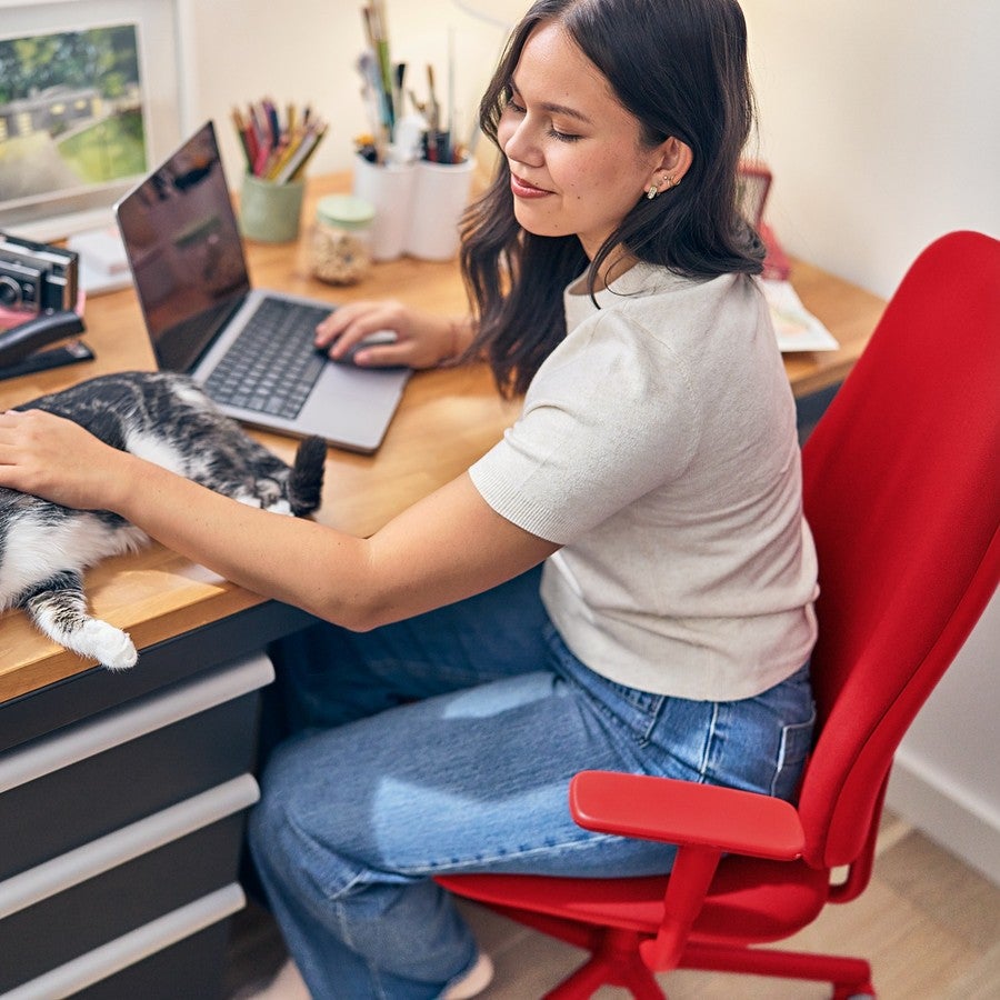 Mujer trabaja en su escritorio junto a su gato