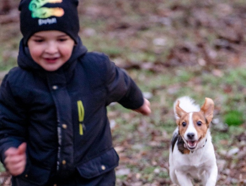 Niño corre junto a su perro en el parque
