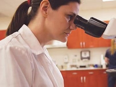 Investigadora observa por un microscopio